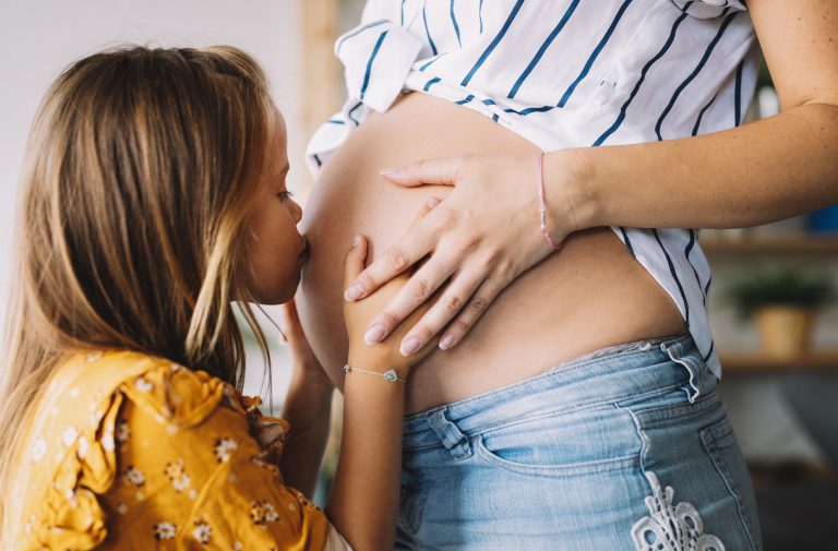 Enfant embrassant le ventre rond de sa maman enceinte