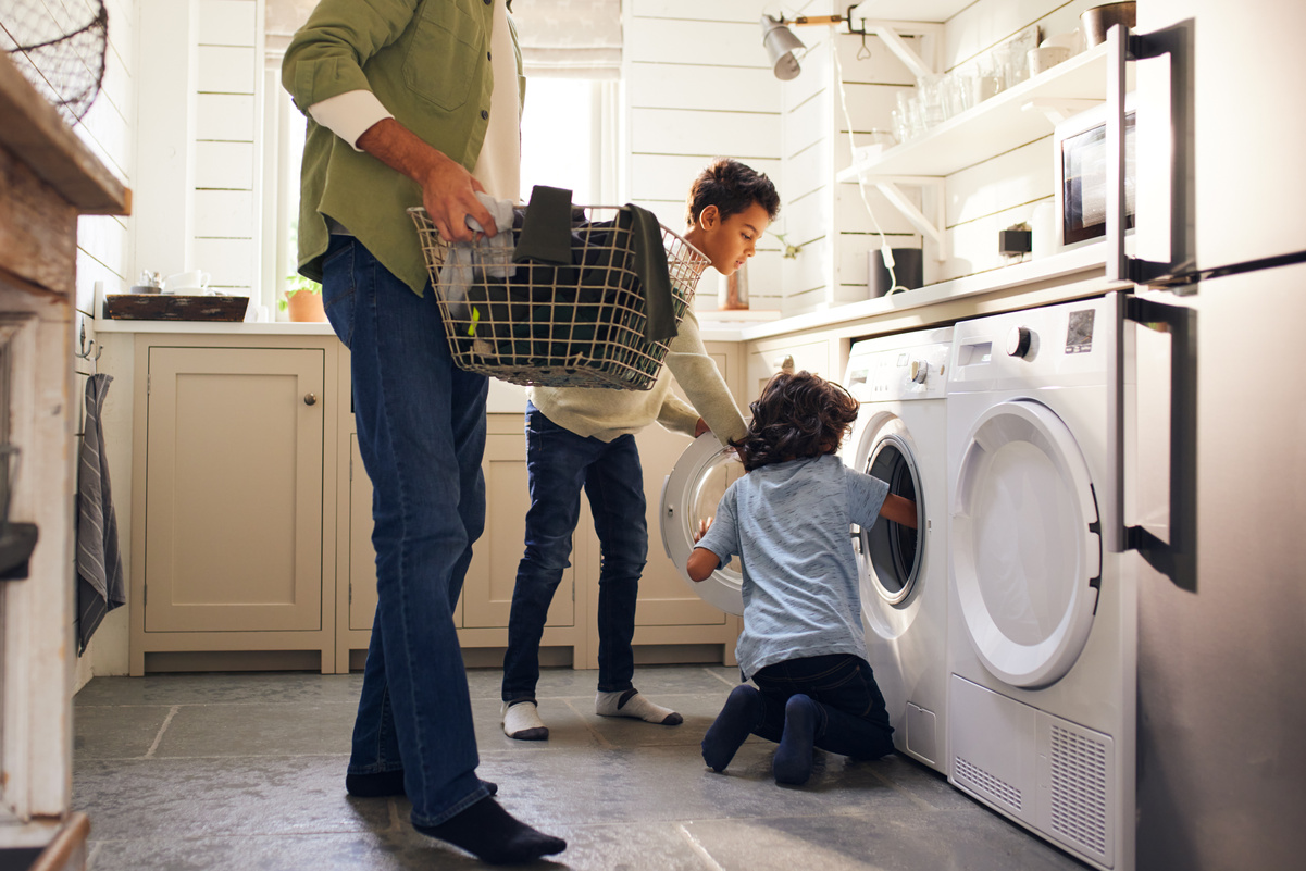 Homme avec enfants devant machine à laver équipement
