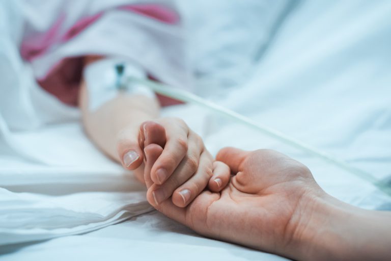 enfant malade hospitalisé tenant la main de sa mère