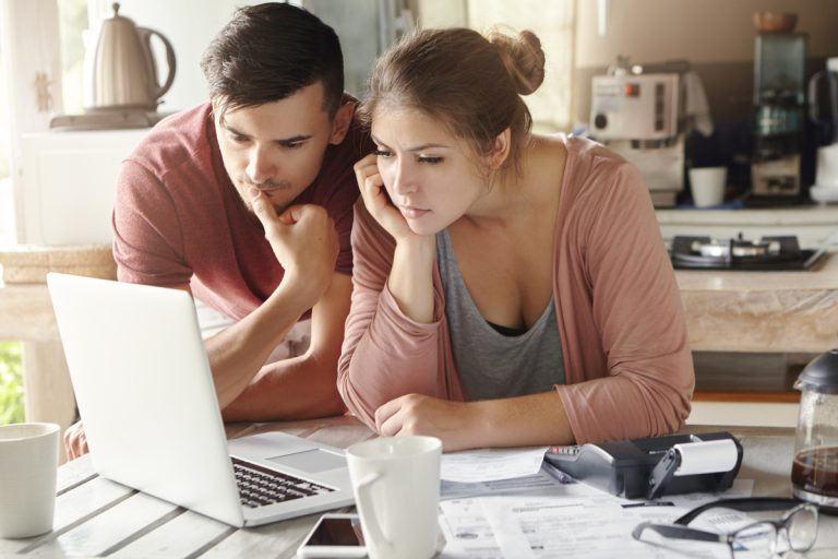 Jeune couple devant ordinateur se connectant au site de la CAF