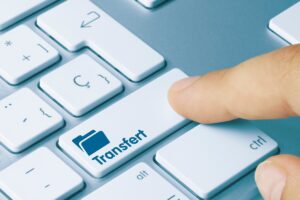 Touche de clavier avec dossier bleu illustrant le transfert de dossier MSA à la CAF.