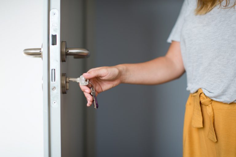 Femme propriétaire ouvre porte logement loué clefs
