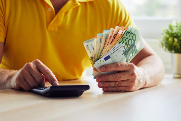 Homme tenant billets euros + calculette