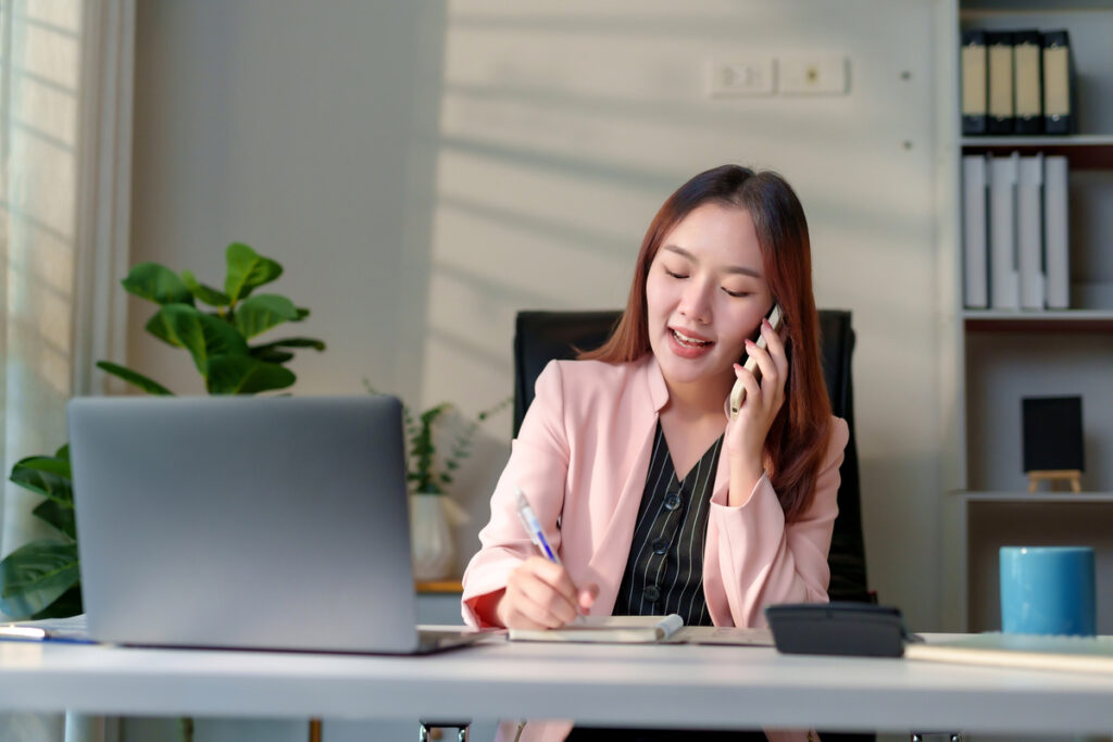Femme au téléphone préparant sa déclaration RSA et impôts avec sérieux pour éviter les erreurs de saisie.