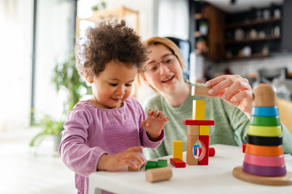 Assistante maternelle jouant avec un enfant, base de calcul crédit d'impôt garde d'enfants 2026