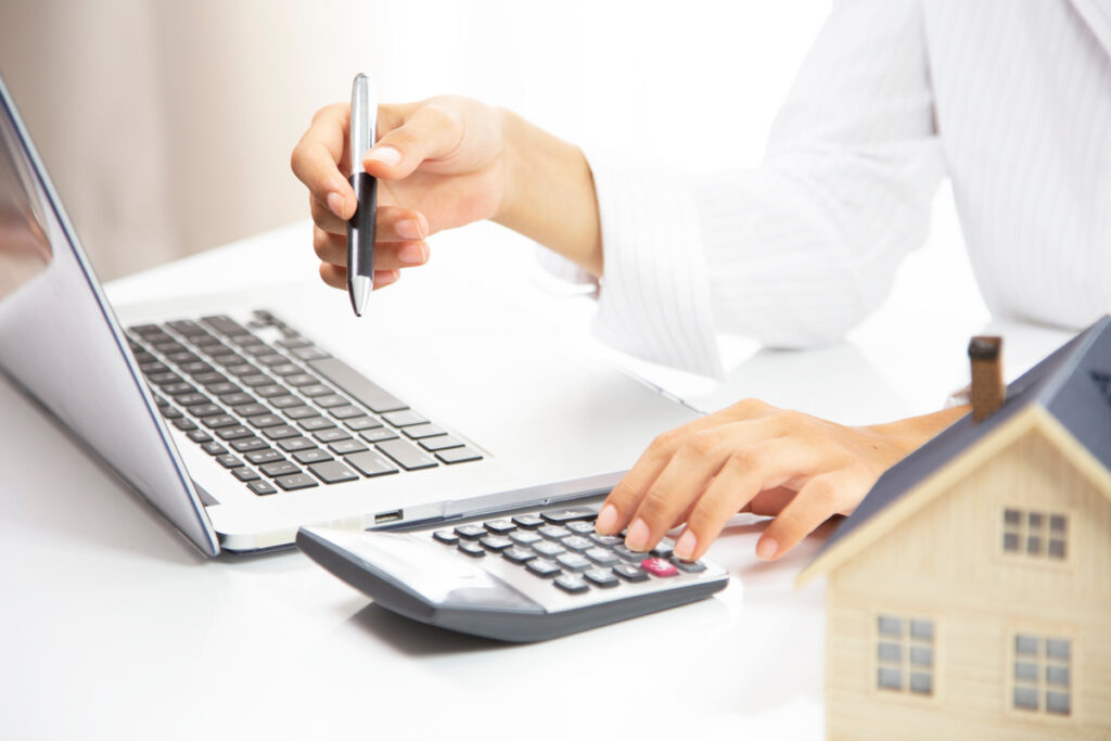 Personne utilisant une calculatrice et un ordinateur pour simuler le montant de son APL 2026.