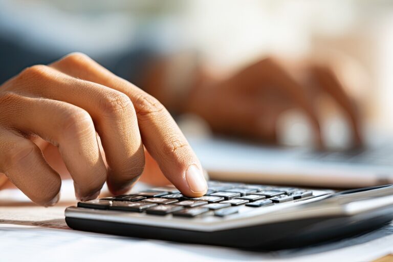 Gros plan sur une personne utilisant une calculatrice pour sa déclaration de revenus 2026 afin d'éviter une suspension de la CAF.