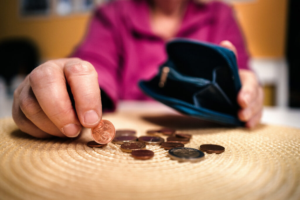 Gros plan sur des pièces d'un euro et un portefeuille vide illustrant un calcul reste à vivre CAF critique.