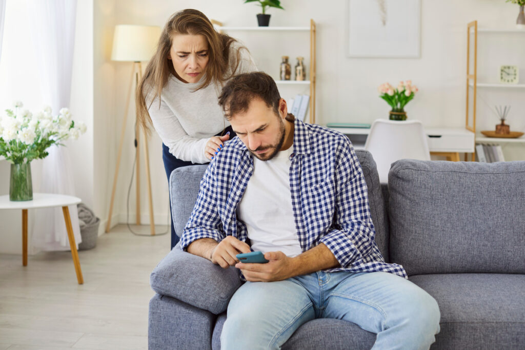 Un couple inquiet dans son salon face à une notification de suspension CAF sur smartphone.