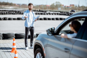 Moniteur d'auto-école évaluant une candidate au permis de conduire sur un circuit de conduite.
