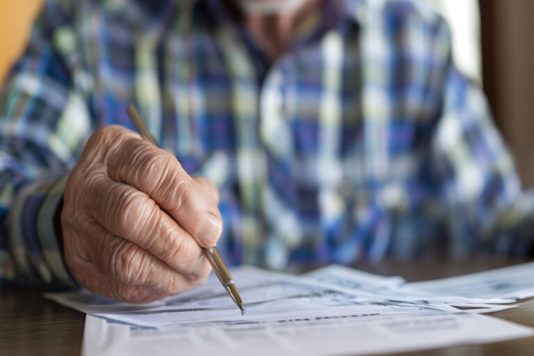 Gros plan sur la main d'un allocataire remplissant un formulaire administratif de la CAF.