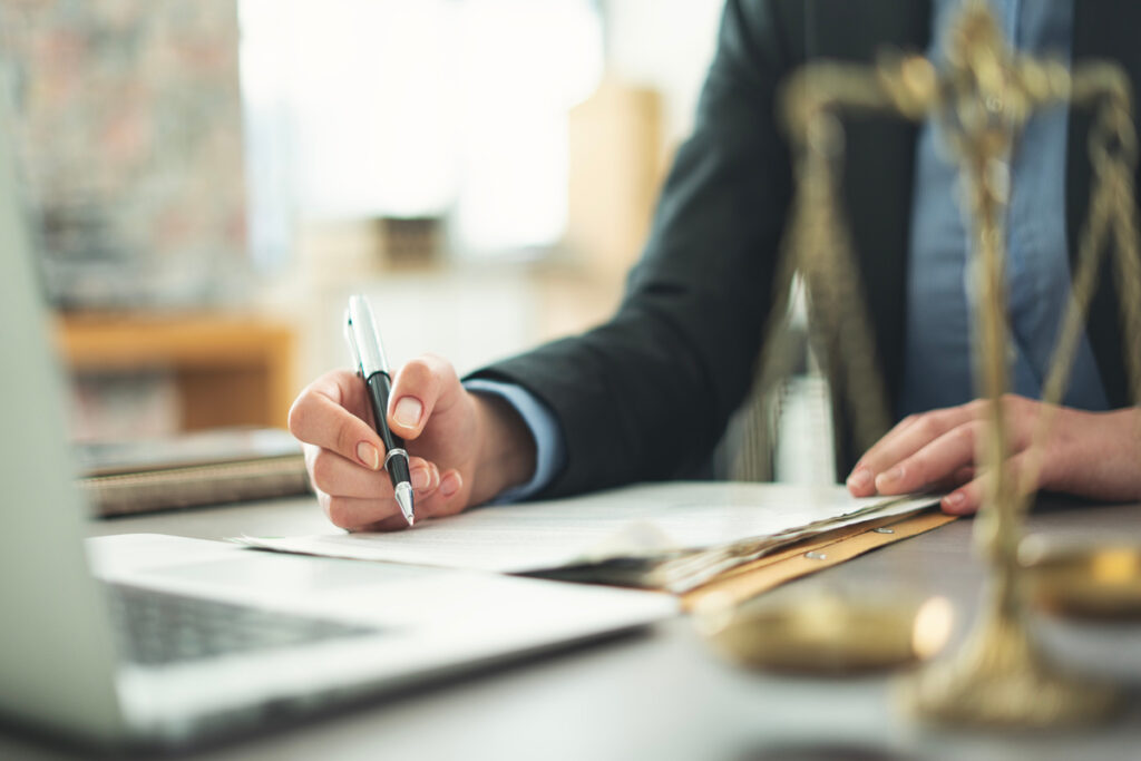 Signature d'un formulaire administratif à côté d'une balance de justice pour valider ses droits AAH 2026.