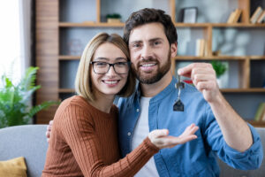 Couple souriant tenant les clés de leur nouveau logement après obtention des aides au logement.