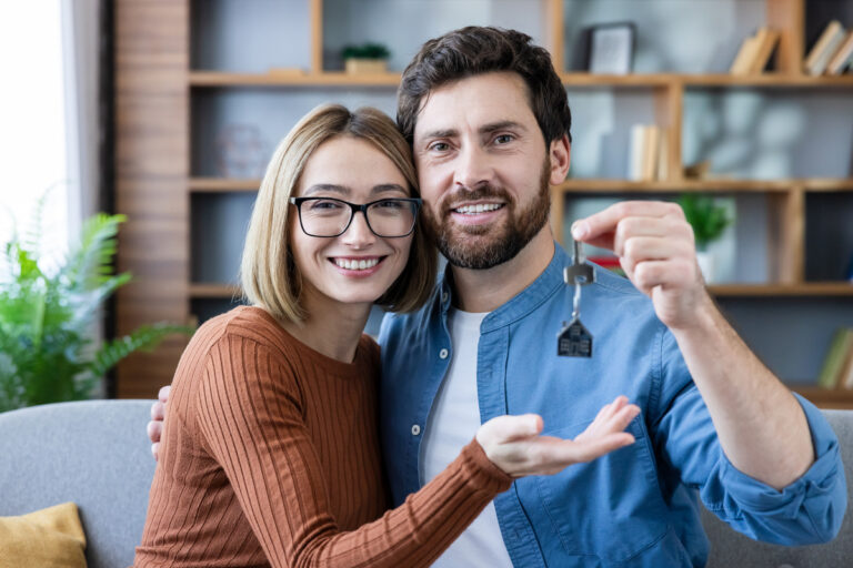 Couple souriant tenant les clés de leur nouveau logement après obtention des aides au logement.