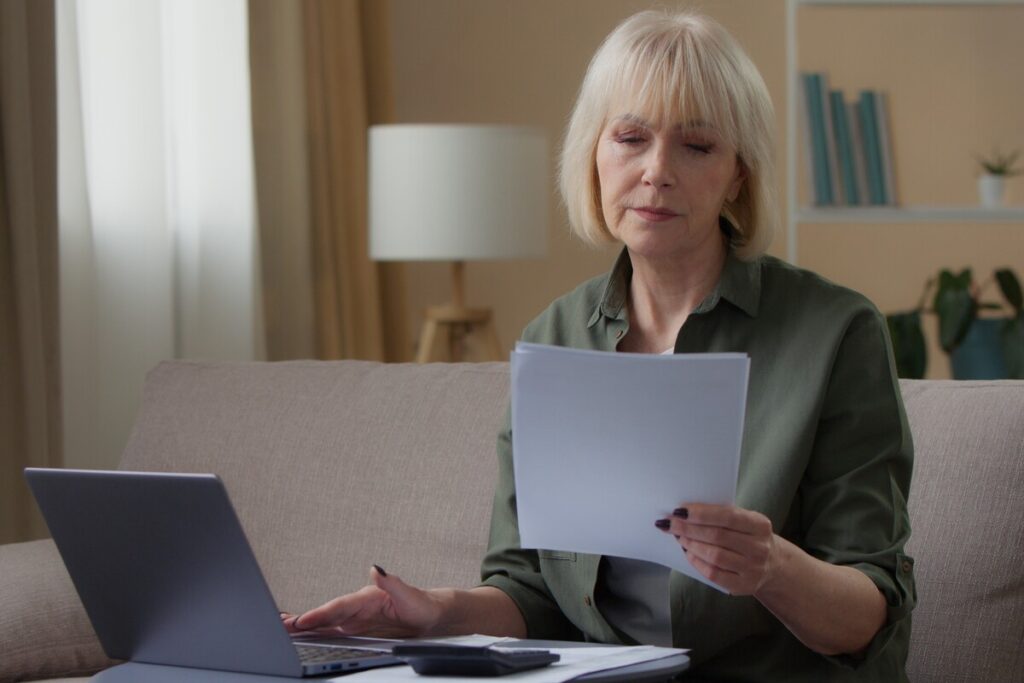 Femme organisant ses documents administratifs pour préparer une demande de remise de dette CAF.