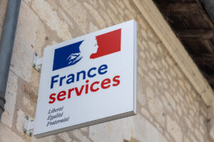 Enseigne officielle France Services fixée sur un mur en pierre pour aider les usagers face à un problème de dossier CAF.
