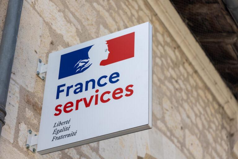 Enseigne officielle France Services fixée sur un mur en pierre pour aider les usagers face à un problème de dossier CAF.