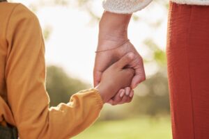 Main d'un parent tenant celle d'un enfant pour illustrer l'Allocation de Soutien Familial (ASF).