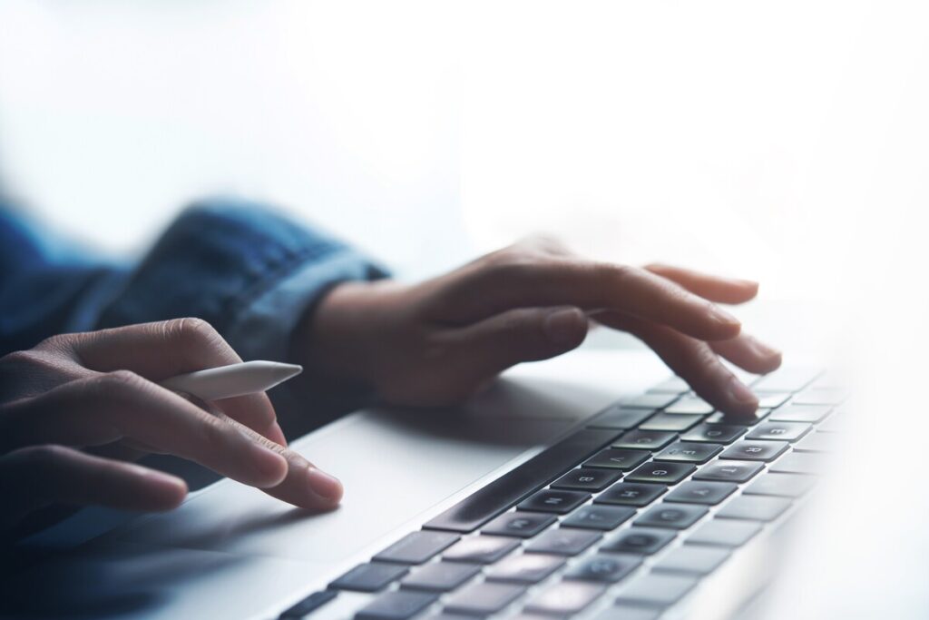 Mains saisissant des chiffres sur un clavier pour déclarer les revenus auto-entrepreneur CAF en ligne