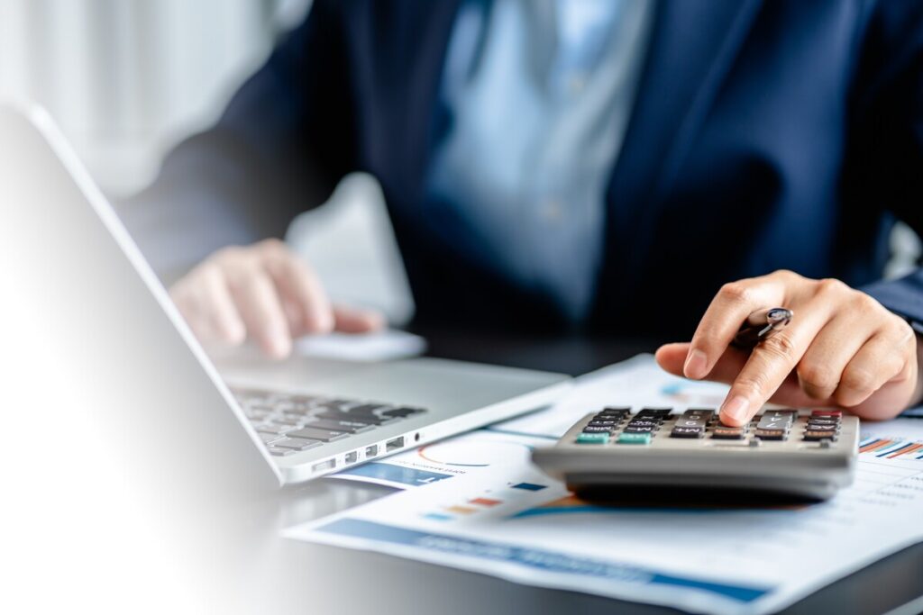 Personne utilisant un ordinateur et une calculatrice pour effectuer une simulation d'aide au logement