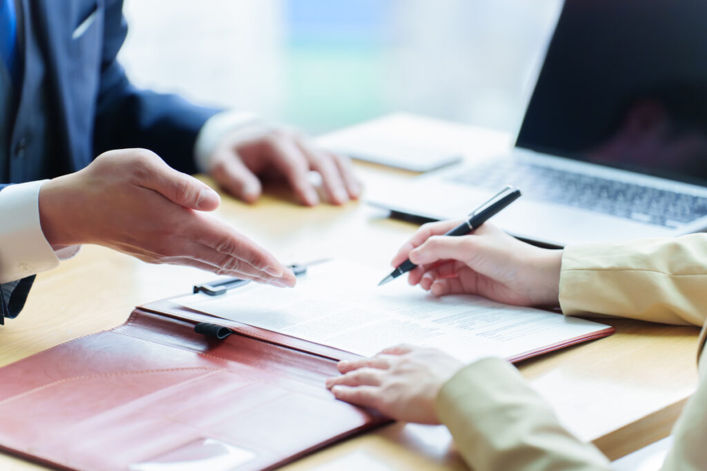 Un conseiller et un jeune signant des documents administratifs pour formaliser le Contrat d’Engagement Jeune.