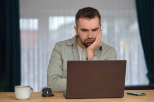 Homme inquiet devant son ordinateur attendant le versement de l'ARS non reçue.