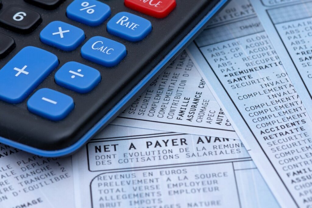 Gros plan sur un bulletin de paie et une calculatrice pour distinguer le salaire net du MNS