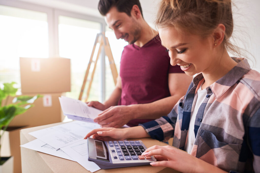 Couple calculant son budget et remplissant des documents administratifs pour une demande d'aide au logement CAF après un déménagement