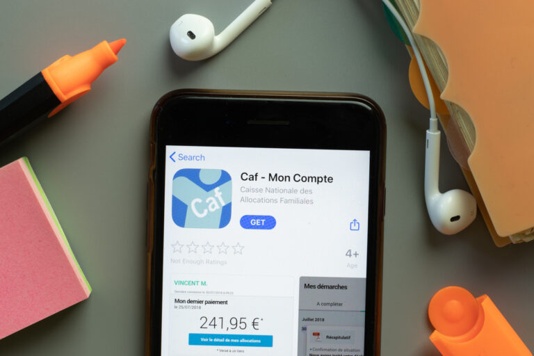 Smartphone affichant l'application Caf - Mon Compte sur un bureau de travail