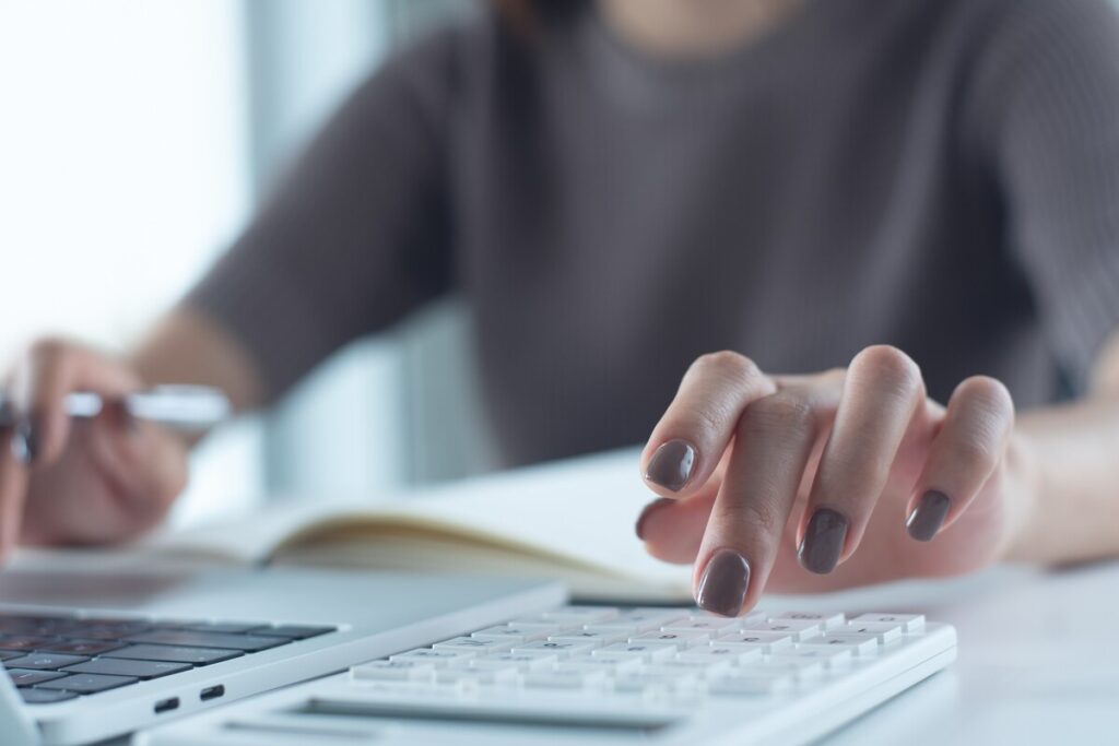 Main utilisant une calculatrice et un ordinateur pour corriger une erreur DSN de Montant Net Social