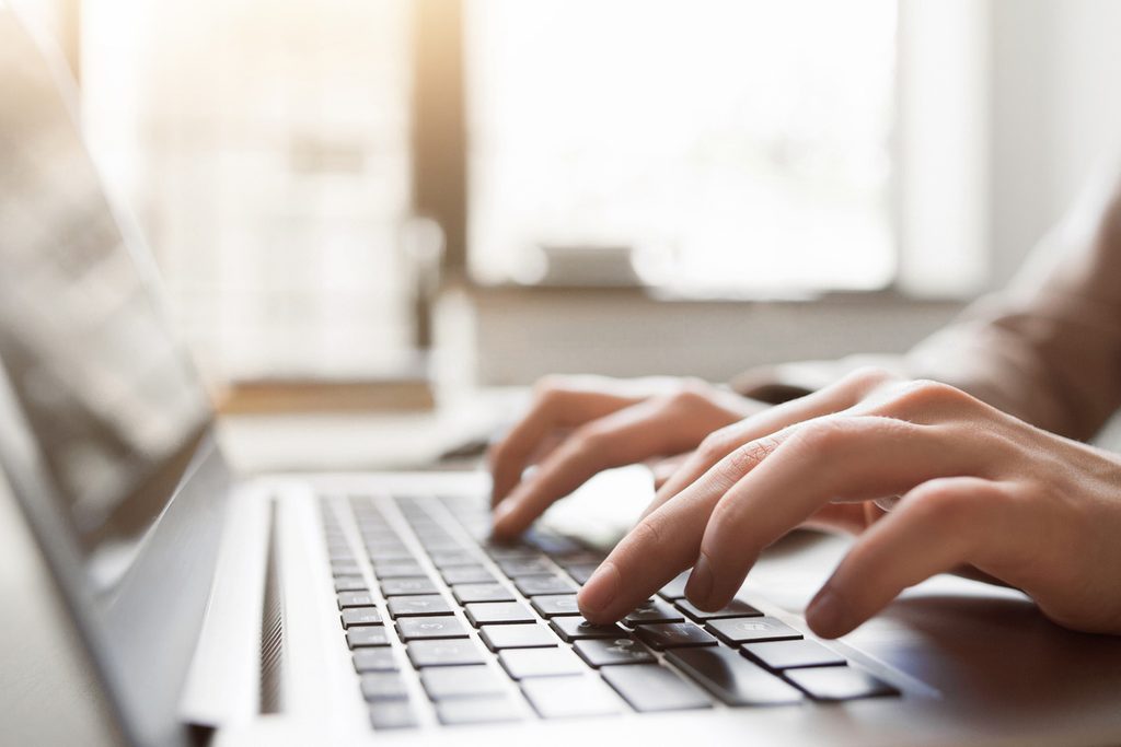 Mains saisissant des informations sur un clavier d'ordinateur pour faire la demande d'aide carburant 2026
