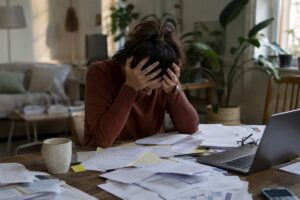Personne stressée face à des factures et des documents administratifs, symbolisant le surendettement CAF.