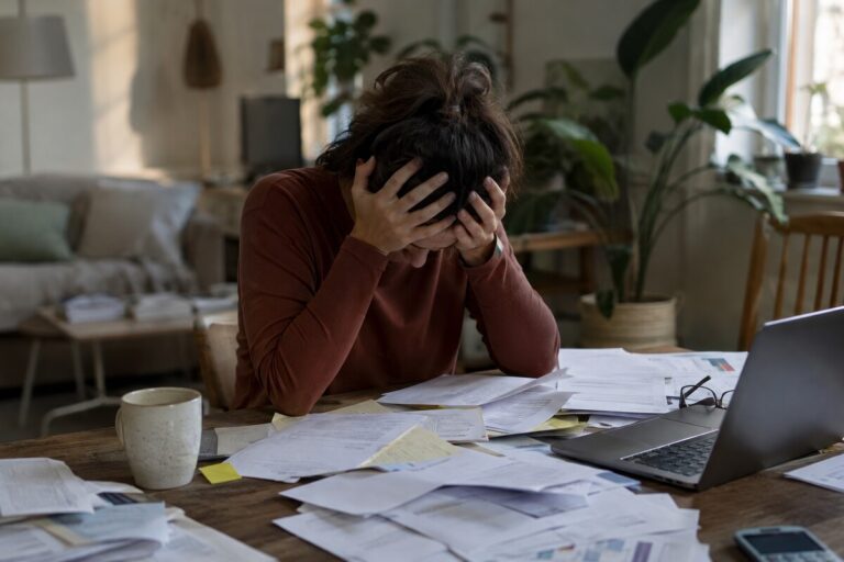 Personne stressée face à des factures et des documents administratifs, symbolisant le surendettement CAF.