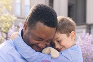 Un tiers digne de confiance enlacé chaleureusement avec l'enfant mineur qu'il accueille au foyer.